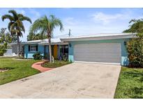 Charming blue single-story home with well-manicured lawn, mature landscaping, and a two-car garage at 13979 Barbados Dr, Seminole, FL 33776