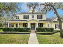 Charming yellow two-story home with a covered front porch, columns, and well-manicured landscaping at 16113 Ternglade Dr, Lithia, FL 33547
