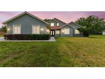 Charming home featuring a well-manicured lawn, lush shrubbery and a red tile roof at 18502 Keystone Manor Rd, Odessa, FL 33556