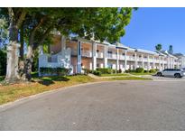 Low angle view of a multi-Gathering, two story building with white paint, multiple balconies and a car parked on the right at 2291 Americus W Blvd # 23, Clearwater, FL 33763