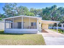 Charming home featuring a covered porch, carport, and well-maintained front yard, creating a welcoming curb appeal at 34834 Carl Ave, Zephyrhills, FL 33541
