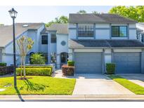 Two-story townhouse with a well-manicured lawn, gray exterior and gray garage doors at 4146 Brentwood Park Cir, Tampa, FL 33624