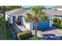 Charming single-story home with a blue garage door, paver driveway and walkway, and lush tropical landscaping at 5415 Los Robles Ct, Palmetto, FL 34221