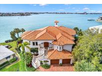 Stunning waterfront home with a vibrant terracotta roof and lush landscaping, offering picturesque views at 5630 Bayview Dr, Seminole, FL 33772
