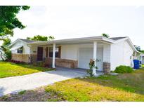 Charming single-story home with white siding, stone accents, and a well-manicured lawn at 7435 Hollyridge Dr, New Port Richey, FL 34653