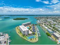 Breathtaking aerial view of a waterfront condo community with a pool and tennis court, surrounded by beautiful turquoise waters at 1 Key Capri # 301E, Treasure Island, FL 33706