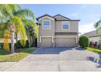 Two-story home featuring a three-car garage, and a well maintained lawn and palm tree at 1564 Imperial Key Dr, Trinity, FL 34655