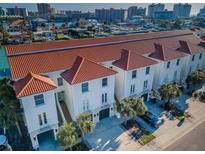 Aerial view of a row of white two-story townhouses with red roofs and well-manicured landscaping at 161 Brightwater Dr # 8, Clearwater Beach, FL 33767