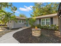 Charming single-story home with a cozy front yard featuring a stone fire pit and mature landscaping at 320 Lake Maggiore S Blvd, St Petersburg, FL 33705
