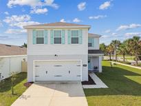 Two-story home with light blue shutters and a two car garage, complemented by a well-manicured lawn at 35168 Arya Way, Zephyrhills, FL 33541