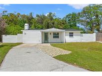 Charming single-story home featuring a well-manicured lawn, brick walkway, and a lovely light-teal colored front door at 4613 Irene Loop, New Port Richey, FL 34652