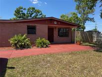 Charming single-story brick home with well-maintained front yard and colorful, red-painted patio at 6420 N Thatcher Ave, Tampa, FL 33614