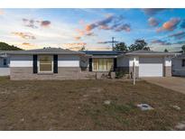 Charming single-story home with a manicured lawn and a classic facade at sunset at 11422 Yellowwood Ln, Port Richey, FL 34668
