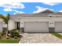 Beautiful home exterior featuring a tile roof, stone accents, and a paved driveway with a well-manicured lawn at 12323 Hearts Ease St, Venice, FL 34293