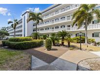 Low-rise condominium exterior with palm trees and manicured landscaping at 131 Bluff View Dr # 101, Belleair Bluffs, FL 33770