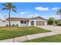 Charming single-story home showcasing a well-maintained lawn, neutral exterior, and a welcoming two-car garage at 2214 Wilshire Dr, Dunedin, FL 34698