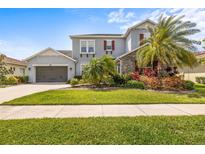 Charming two-story home with lush landscaping, gray stucco, stone accents, and red shutters at 32203 Wenlock Loop, Wesley Chapel, FL 33543