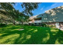 A two-story condo building sits beautifully landscaped with green lawn and mature trees providing ample shade at 36750 Us 19 N Hwy # 18-210, Palm Harbor, FL 34684