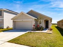 Charming one-story home with a well-maintained lawn and a two-car garage on a sunny day at 659 Sunlit Coral St, Ruskin, FL 33570