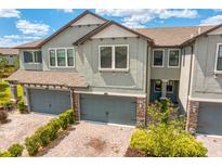 Two-story townhome with brick paver driveway, gray garage doors, and manicured landscaping at 4663 Almada Ln, Wesley Chapel, FL 33543
