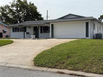 Charming single-story home with a well-manicured front yard and a wide driveway leading to an attached two-car garage at 14264 Page Ave, Largo, FL 33774