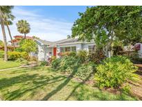 Charming single-story home featuring lush landscaping, a manicured lawn, and a vibrant red front door at 615 14Th Ne Ave, St Petersburg, FL 33701