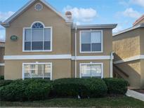 Two-story condo building with manicured landscaping, crisp white trim, and a light brown facade under a bright blue sky at 9481 Highland Oak Dr # 703, Tampa, FL 33647
