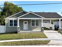 Charming exterior view of a renovated home, featuring a quaint front porch and covered driveway at 107 E Park St, Tarpon Springs, FL 34689