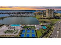 Stunning aerial view of the community amenities including tennis courts, pools, and miniature golf, with the bay in the background at 130 Riviera Dunes Way # 203, Palmetto, FL 34221
