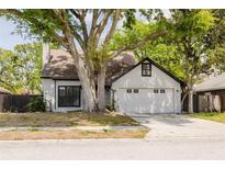 Charming home featuring a white brick exterior, chimney and a two-car garage nestled beneath a mature tree at 7227 Otter Creek Dr, New Port Richey, FL 34655