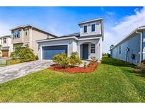 Charming two-story home with manicured lawn, a paved driveway, and attached garage in a quiet neighborhood at 7334 Ashcroft Dr, Wesley Chapel, FL 33545