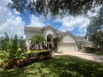 Charming two-story home featuring lush landscaping, a well-manicured lawn, and a terracotta-tiled roof at 9980 Sago Point Dr, Seminole, FL 33777