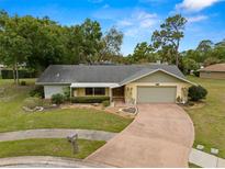 Charming single-story home with a well-maintained front yard, mature trees, and attached two-car garage at 112 Rosewood Ct, Palm Harbor, FL 34685