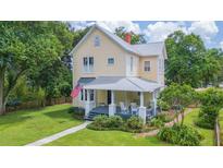 Charming two-story home with a welcoming front porch, complemented by a lush green lawn and mature trees at 14006 5Th St, Dade City, FL 33525