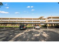 Exterior of a condominium building with covered parking on a sunny day, ample parking spaces, and well-maintained landscaping at 5080 Locust Ne St # 321, St Petersburg, FL 33703