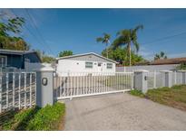 Charming single-story home featuring a gated entrance, white picket fence, and lush landscaping at 7006 N Duncan Ave, Tampa, FL 33604