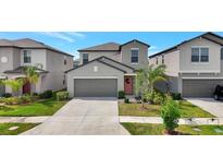Charming two-story home with a well-manicured lawn, gray exterior, and attached two-car garage at 7331 Canterbury Bells Ct, Tampa, FL 33619