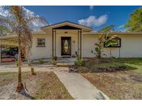 Charming home featuring a covered front entrance with a decorative front door and manicured landscaping at 9802 Eden Ave, Hudson, FL 34667