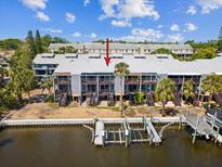 Waterfront condo building with private docks, balconies, and lush tropical landscaping showcasing a desirable coastal lifestyle at 200 Meres Blvd # 26, Tarpon Springs, FL 34689