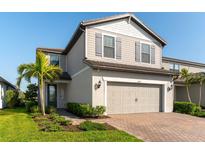 Charming two-story home featuring a well-manicured lawn, neutral siding, and an attached two-car garage with brick paver driveway at 6223 Baywood Ct, Bradenton, FL 34211