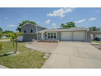 Charming home featuring a two-car garage, brick accents, and a well-maintained front yard under a bright sky at 7015 Cobblewood Ct, Tampa, FL 33615