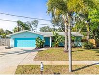 Charming single-story home with a blue exterior, well-manicured lawn, and lush tropical landscaping at 1596 Idle Dr, Clearwater, FL 33756