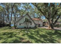 Charming two-story lakefront home with beautiful landscaping, mature trees, and large grassy yard at 16019 Chastain Rd, Odessa, FL 33556