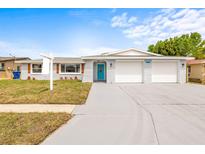 Charming single-story home features a blue front door, a two car garage, and a well manicured front yard at 6227 12Th Ave, New Port Richey, FL 34653