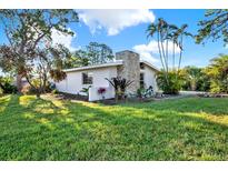 Charming single-story home featuring stone details, manicured lawn, and lush landscaping at 9107 Bay Ne St, St Petersburg, FL 33702