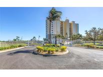 View of the gated entry to a luxury condo building, beautifully landscaped with tropical palms and manicured shrubs at 10851 Mangrove Cay Ne Ln # 714, St Petersburg, FL 33716