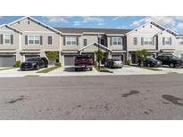 View of townhomes with gray exteriors, dark shutters, driveways, and well-manicured lawns at 10924 Brightleaf Ct, Riverview, FL 33569