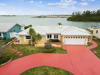 Waterfront home featuring an attached garage, well-manicured yard, and colorful red driveway at 11549 48Th Ave N, St Petersburg, FL 33708