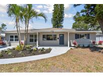 Charming single-story home featuring mature palm trees, fresh landscaping, and a freshly painted walkway to the front door at 1165 63Rd S Ave, St Petersburg, FL 33705
