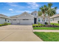 Charming single-story home with a three-car garage, stone accents, paver driveway, and lush landscaping at 19624 Lonesome Pine Dr, Land O Lakes, FL 34638
